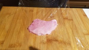 How to make Pork Schnitzel. Place a piece of pork on the plastic wrap.