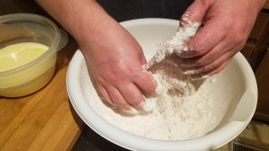How to make Pork Schnitzel. Adding flattened pork cutlet into seasoned flour.