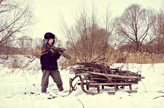 Child gathering sticks / kindling in the winter with a hand pulled sleigh